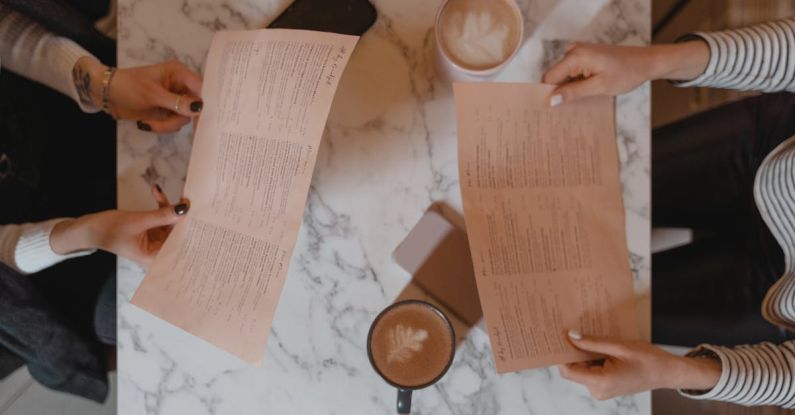 Menus - People Sitting While Holding Menus