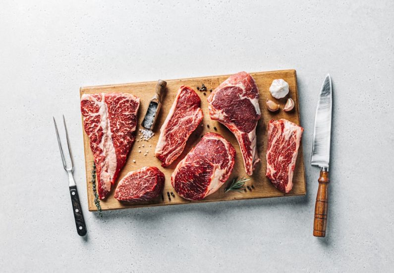 Steakhouses - a cutting board with raw meat and a knife