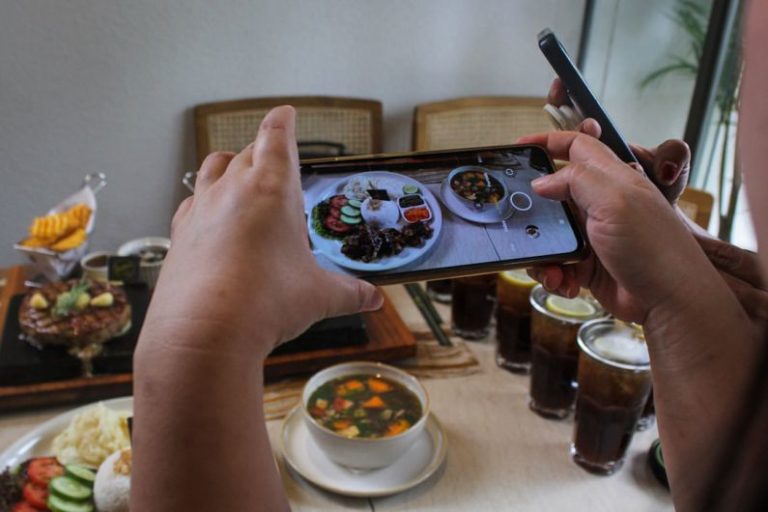 Steakhouses - a person taking a picture of food on a cell phone